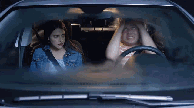 a woman sitting in the back seat of a car with her hands on her head