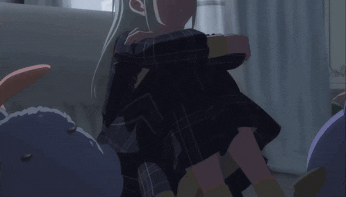 a girl in a plaid dress is sitting on a couch in a dark room