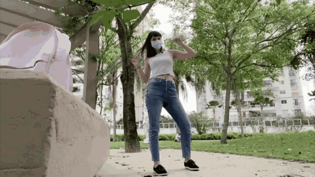 a woman wearing a mask is dancing in the park