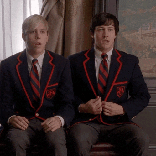 two men wearing school uniforms with a shield on the sleeve