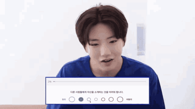 a boy in a blue shirt is looking at a screen with korean writing