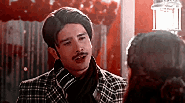 a man with a mustache wearing a plaid jacket and scarf