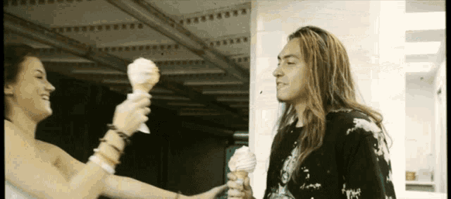 a man and a woman holding ice cream cones in their hands