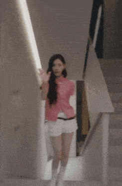a woman in a pink plaid shirt and white shorts is standing in front of a mirror