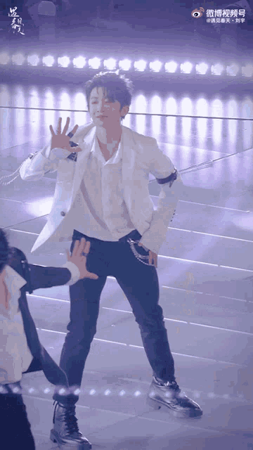a man in a white jacket and black pants dancing on a stage
