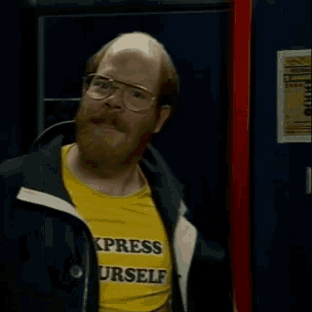 a man with glasses and a beard wears a yellow shirt that says express yourself
