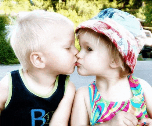 a boy and a girl are kissing and the boy is wearing a shirt with the letter b on the front