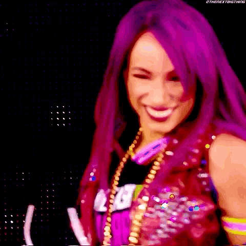 a woman with purple hair is smiling and wearing a red vest and necklace .