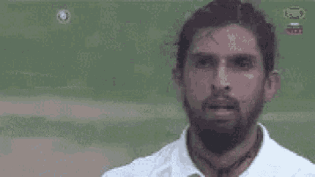 a man with a beard wearing a white shirt and tie is standing on a field .