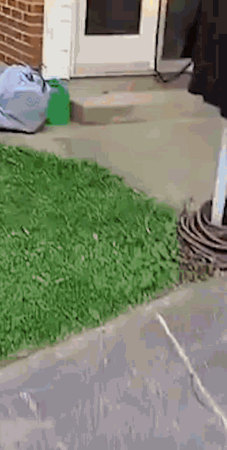a person is standing on a sidewalk in front of a house with a bag on the ground .