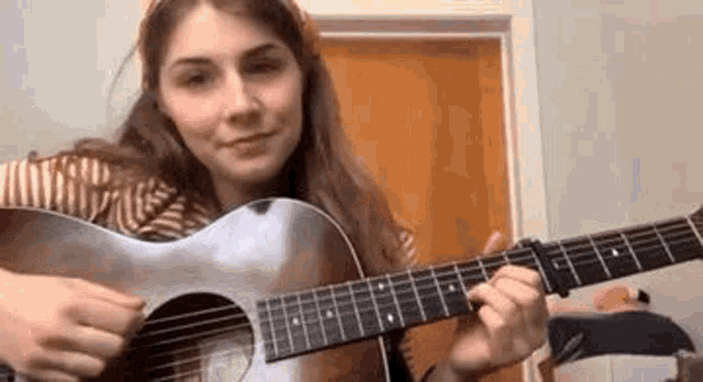 a woman is playing an acoustic guitar in a room .