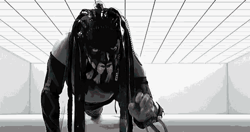 a black and white photo of a woman in a mask and dreadlocks doing push ups .