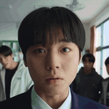 a close up of a young man 's face with a group of people in the background