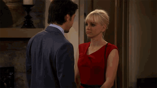 a man in a suit and a woman in a red dress look into each other 's eyes