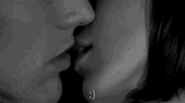 a black and white photo of a man and a woman kissing with a smiley face on their faces .