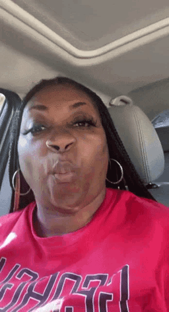 a woman wearing a red shirt that says ' atlanta ' on it is sitting in a car