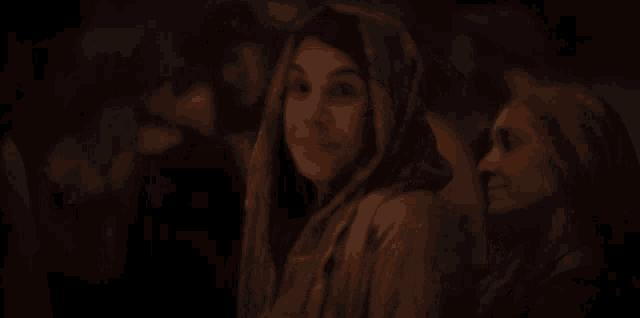 a woman wearing a scarf around her head smiles in a dark room