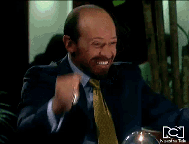 a man in a suit and tie is making a funny face in front of a nuestra tele logo