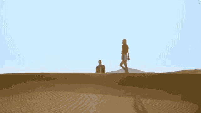a man and a woman are walking through a desert