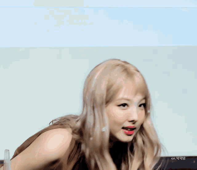 a woman with blonde hair is making a funny face behind a clear barrier