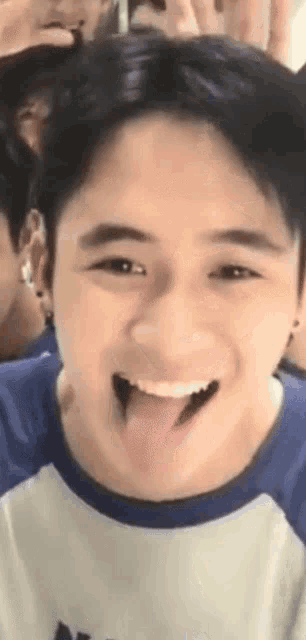 a young man is sticking his tongue out and smiling while looking at the camera .