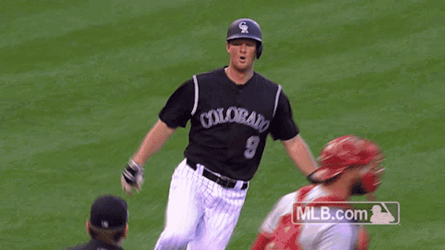 a baseball player for the colorado rockies is running towards home plate