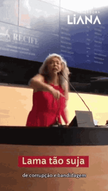 a woman in a red dress stands behind a podium with a sign that says liana