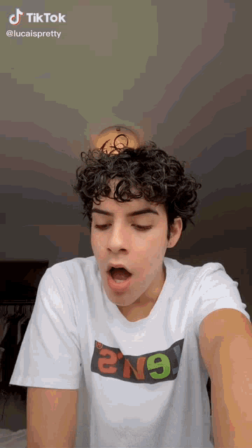a young man with curly hair wearing a white t-shirt that says 2n9