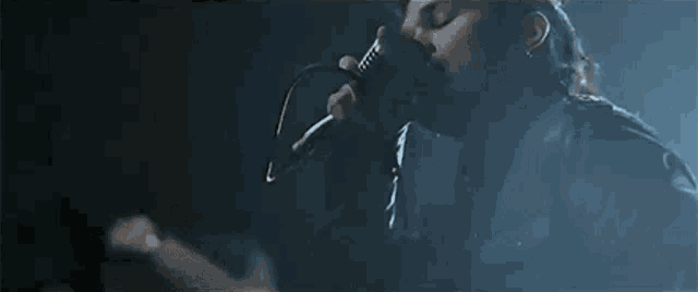 a person is singing into a microphone in a dark room .