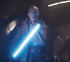 a man in a brown jacket holds a blue light saber