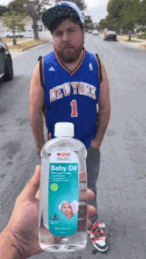 a man wearing a new york jersey holds a bottle of baby oil