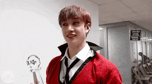 a young man in a red sweater is holding a trophy .