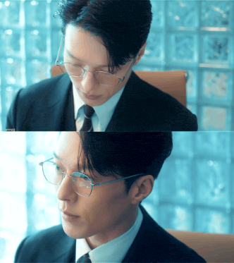 a man in a suit and tie wearing glasses is looking down