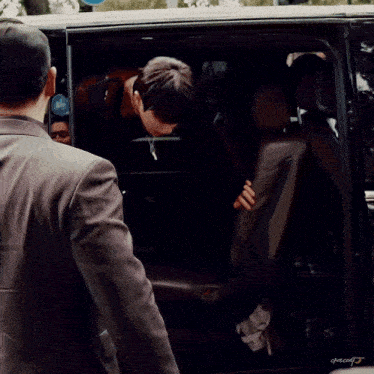 a man in a suit is getting out of a car with a bike sign behind him