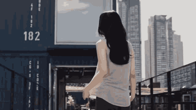 a woman is standing in front of a building that has the number 182 on it