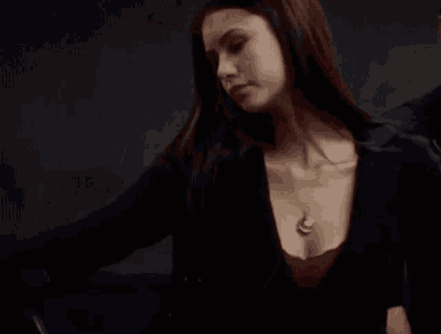 a woman wearing a necklace and a black jacket is looking down .