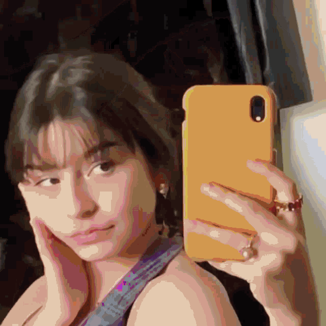 a woman is taking a selfie with her phone in a yellow case .