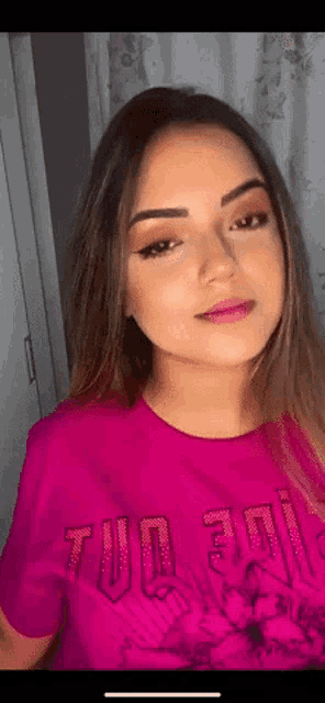 a woman wearing a pink t-shirt with the word tu on it .