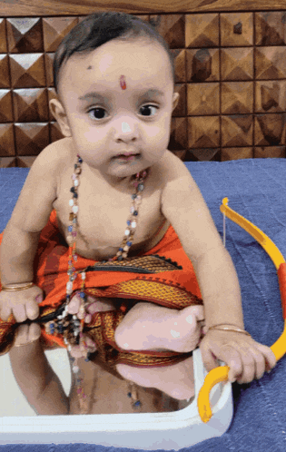 a baby with a red dot on his forehead looks at the camera