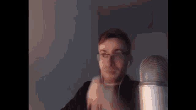 a man wearing headphones is standing in front of a microphone and talking into it .