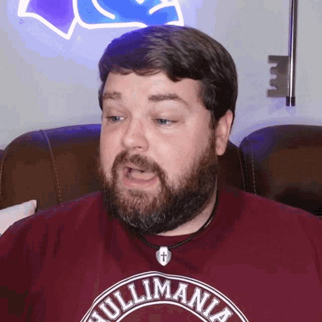 a man with a beard wearing a maroon shirt that says hullmania