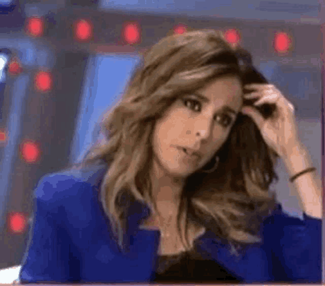 a woman wearing a blue jacket is scratching her head .