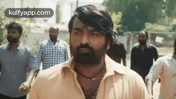 a man with a beard and a necklace is standing in a crowd of people .