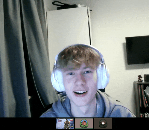 a young man wearing headphones is smiling in front of a screen that shows a video game
