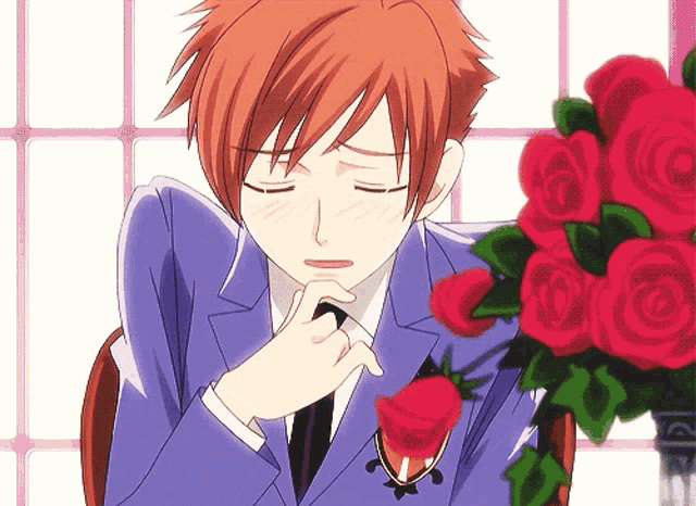 a man in a suit and tie is sitting in front of a vase of roses