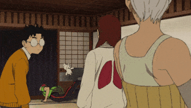 a group of people are standing in a room and one of them has a white shirt with red wings on it