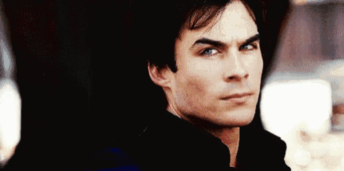 a close up of a man 's face with blue eyes wearing a black jacket .