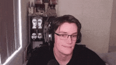 a young man wearing glasses and headphones looks at the camera