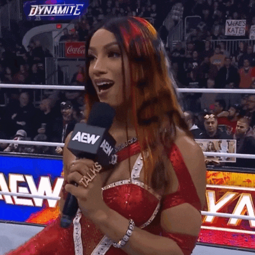 a woman in a red dress is holding a microphone with aew on it