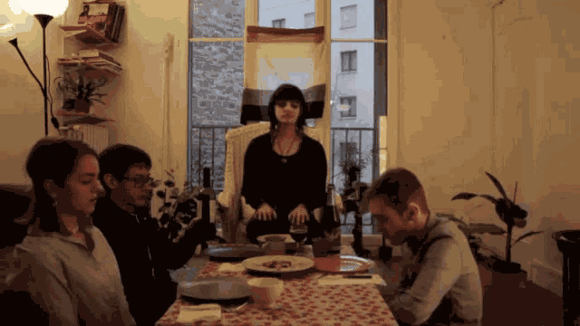 a group of people are sitting around a table with plates and glasses